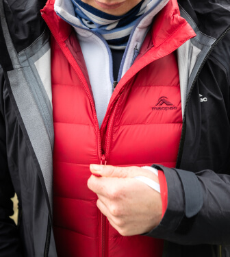 Person zipping up red uber jacket with layers