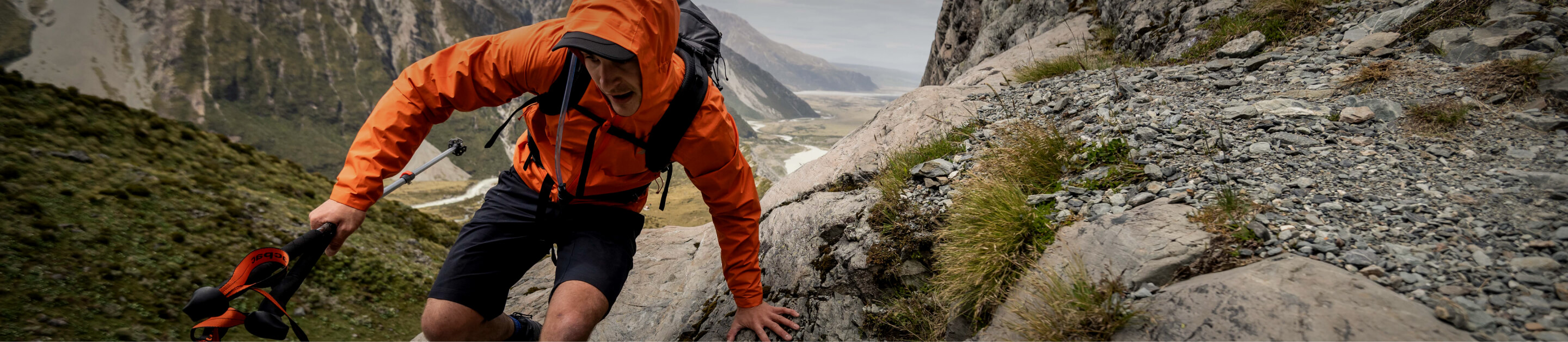 person in orange jacket on rocks